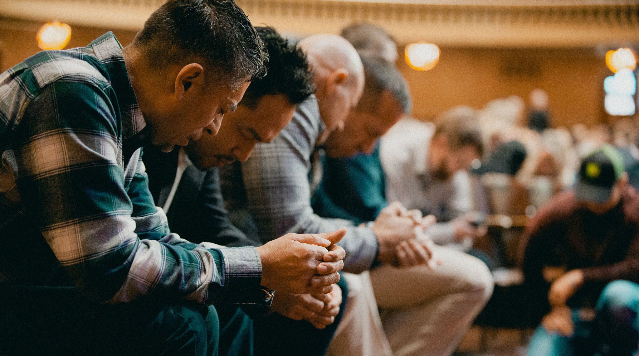 men are bowed in prayer together