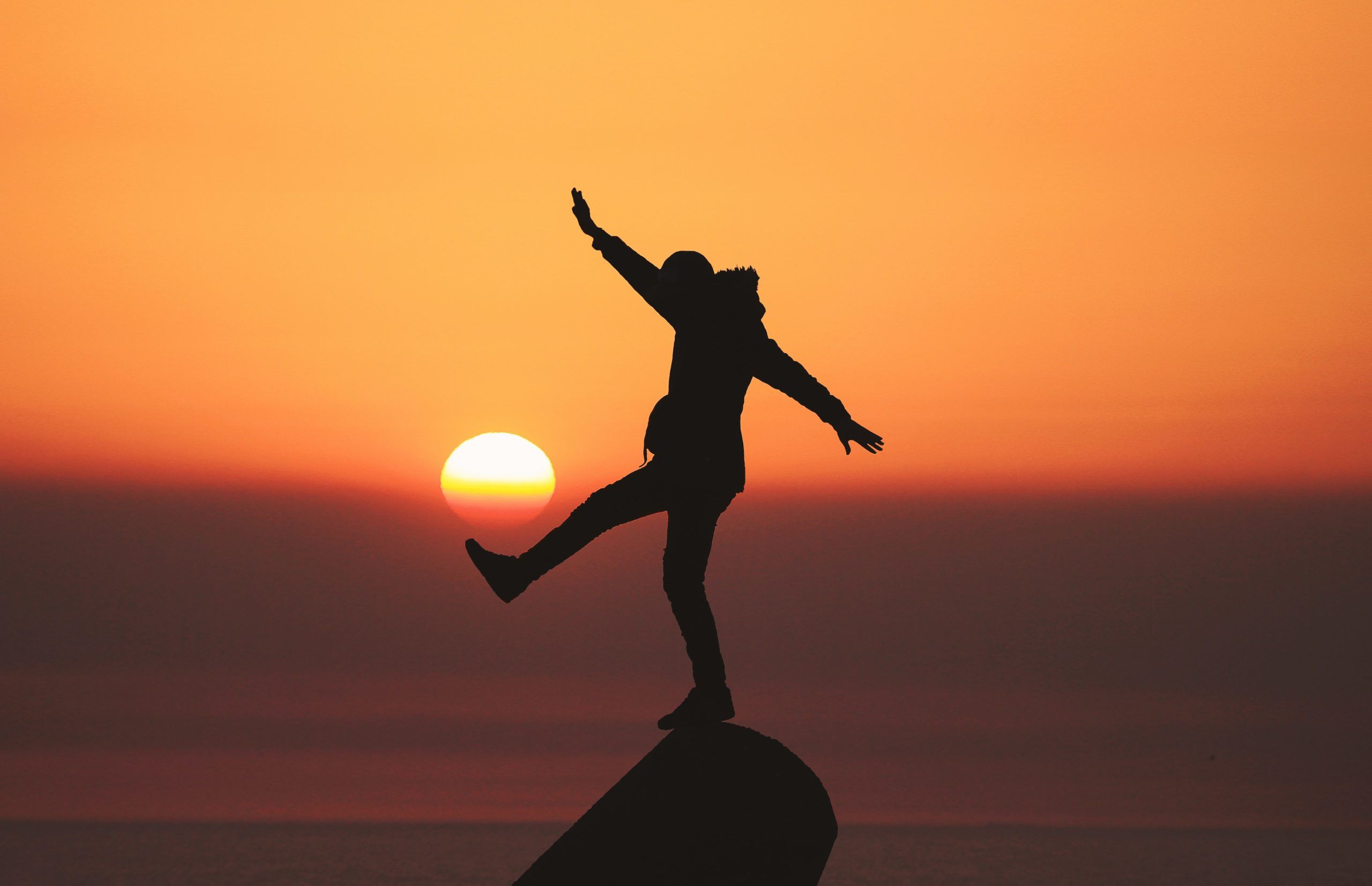 Man balances on rock at sunset