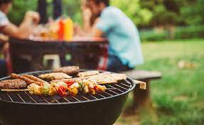 A backyard cookout grill with vegetables and hot dogs
