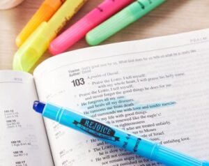 an open bible with a blue highlighter for studying and making notes